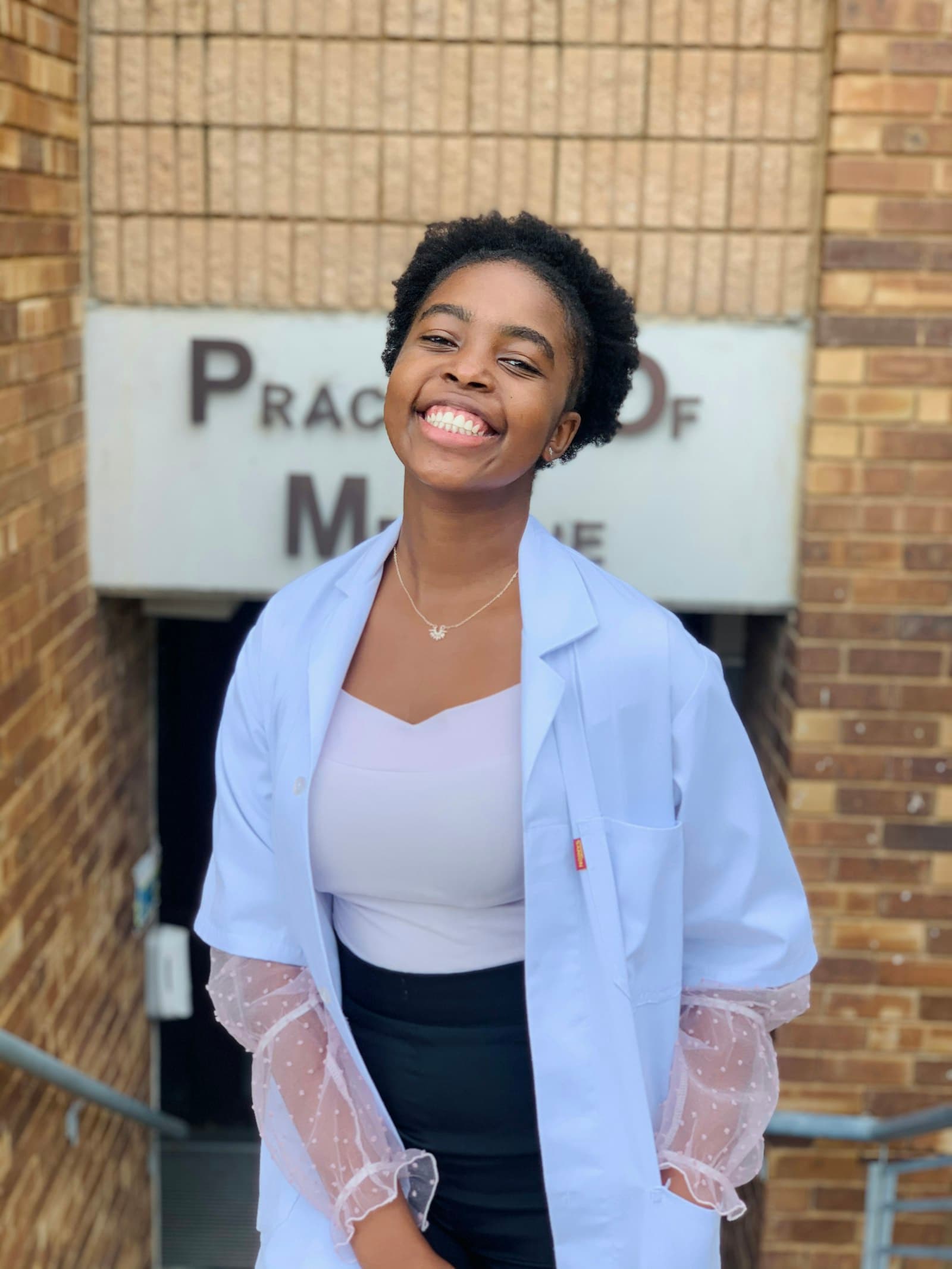 A smiling pharmacy student in a white coat