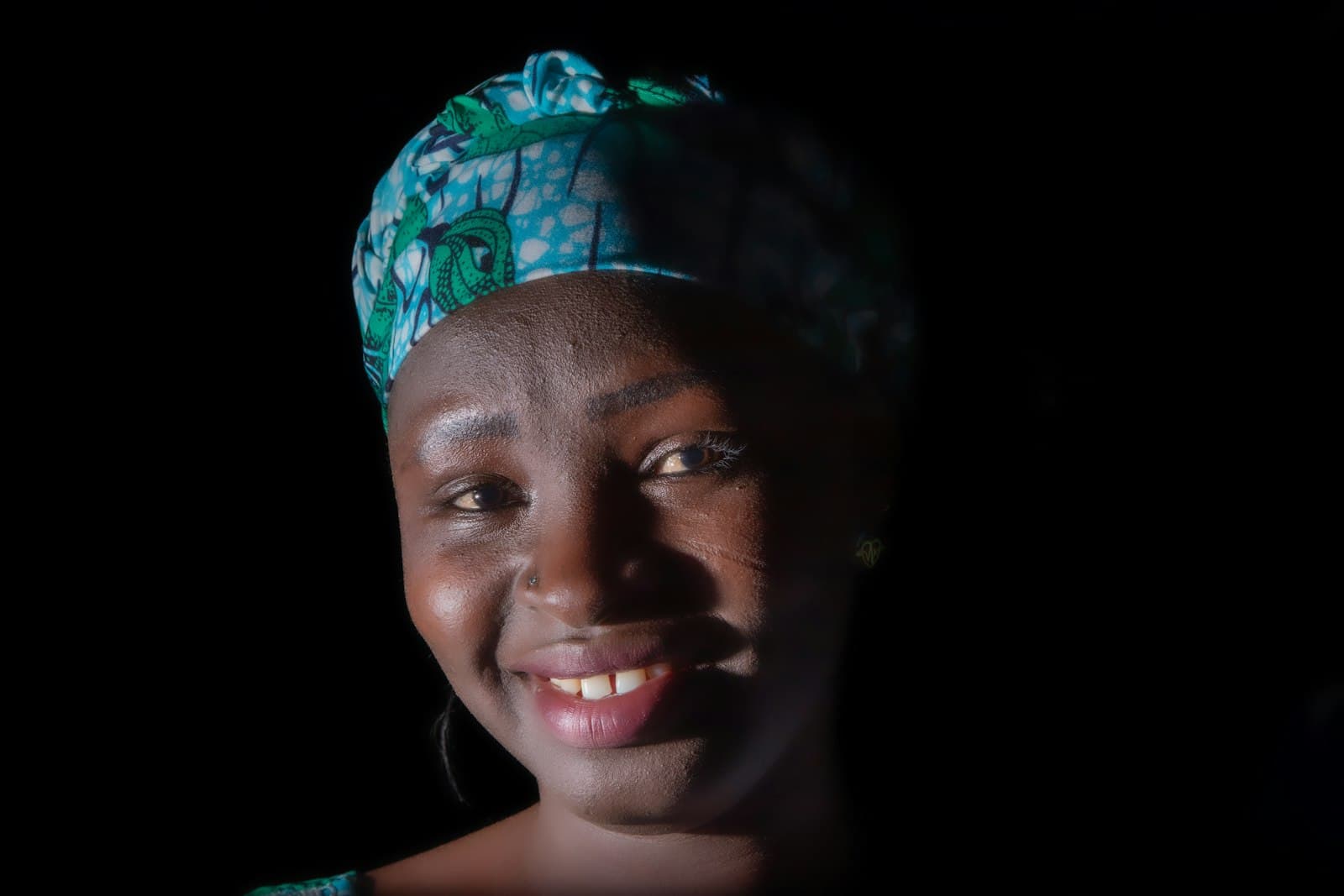 A smiling woman in a patterned headscarf